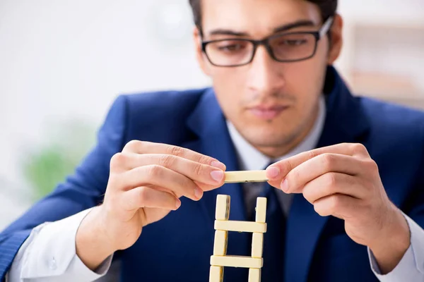Young businessman building domino tower in office — Stock Photo, Image