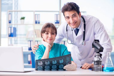 İki doktor hastanede röntgen görüntüsünü tartışıyor.