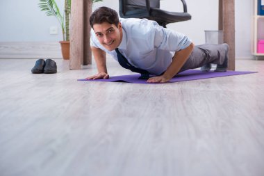 İş adamı tatilde ofiste spor yapıyor.