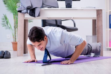 İş adamı tatilde ofiste spor yapıyor.
