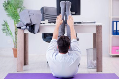 İş adamı tatilde ofiste spor yapıyor.