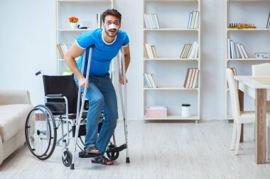 Genç adam ameliyattan sonra koltuk değnekleriyle evde iyileşiyor.