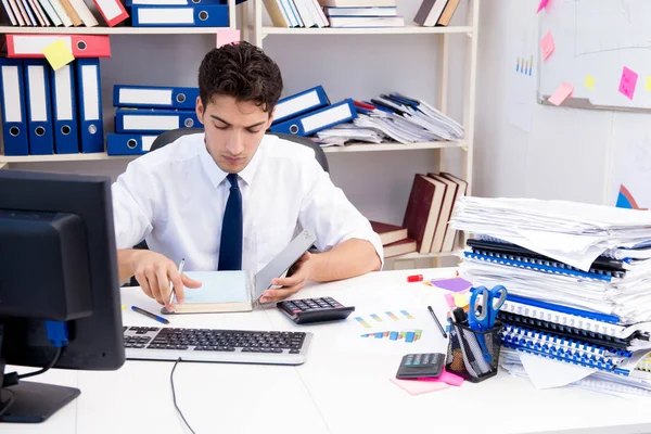 Homme d'affaires travaillant dans le bureau avec des piles de livres et de papiers — Photo