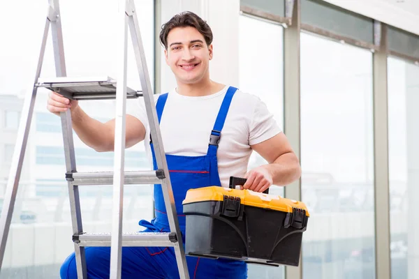 Jovem reparador subindo escada no local de construção — Fotografia de Stock