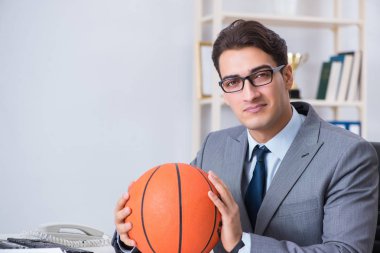 Genç işadamı tatilde ofiste basketbol oynuyor.