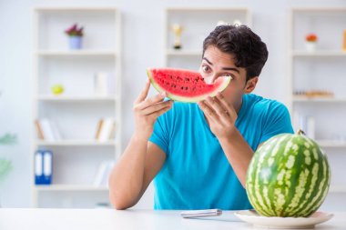 Evde karpuz yiyen bir adam.