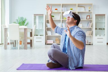 Sanal gerçeklik gözlüğü takan adam evde spor yapıyor.