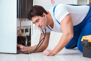 Tamirci müteahhit DIY konseptinde buzdolabını tamir ediyor.