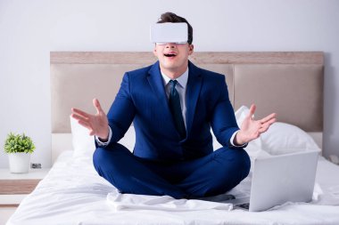 Yatak odasında sanal gerçeklik kulaklığı takan bir iş adamı.