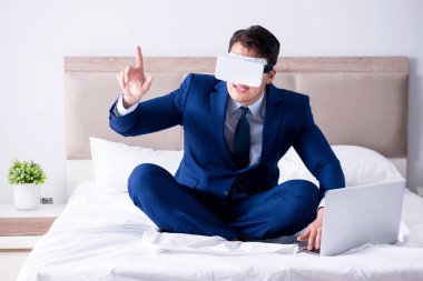 Yatak odasında sanal gerçeklik kulaklığı takan bir iş adamı.