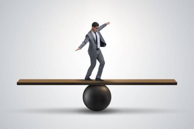 Top ve tahterevalli üzerinde denge kurmaya çalışan bir işadamı