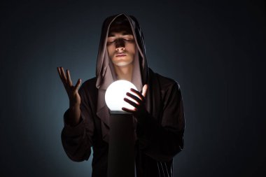 Karanlık odada kristal küreli genç büyücü