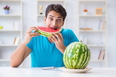Evde karpuz yiyen bir adam.