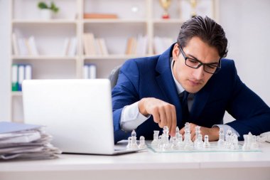 Genç işadamı ofiste cam satranç oynuyor.