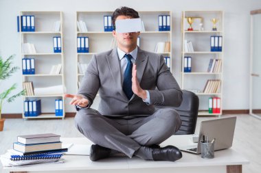 Sanal gerçeklikteki iş adamı VR gözlükleri masanın üstünde meditasyon yapıyor.