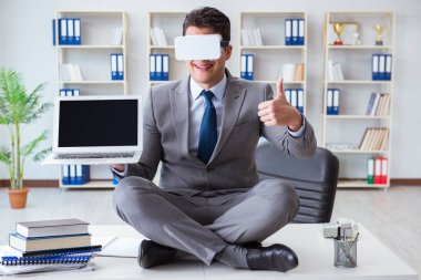 Sanal gerçeklikteki iş adamı VR gözlükleri masanın üstünde meditasyon yapıyor.