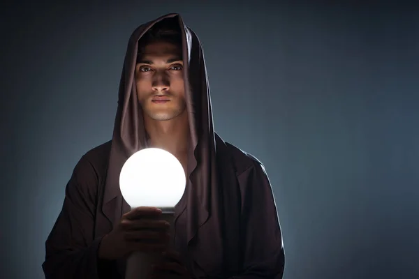 Joven mago con bola de cristal en habitación oscura — Foto de Stock