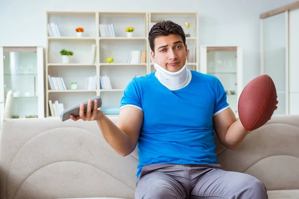 Homem com lesão no pescoço assistindo futebol americano em casa — Fotografia de Stock