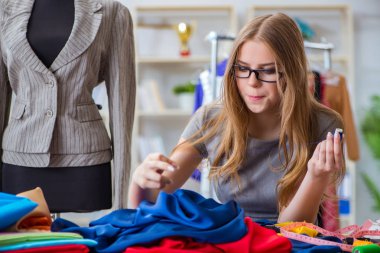 Atölyede çalışan genç bayan terzi yeni elbise üzerinde çalışıyor.