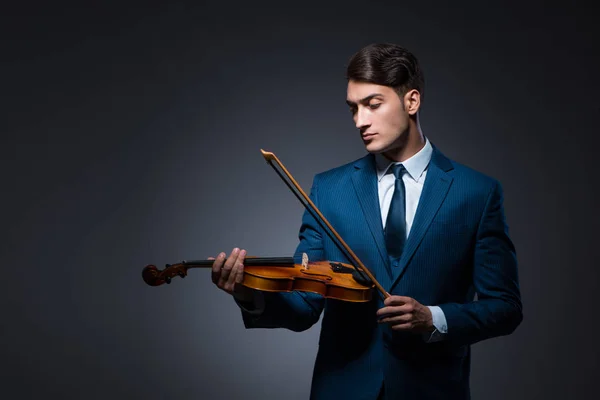 Young man playing violin in dark room — Stock Photo, Image