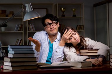 İki öğrenci geç saatlere kadar çalışıp sınavlara hazırlanıyor.