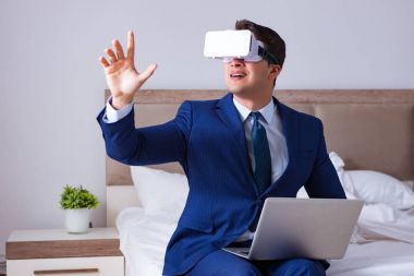Yatak odasında sanal gerçeklik kulaklığı takan bir iş adamı.