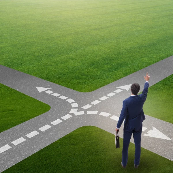 Young businessman at crossroads in uncertainty concept — Stock Photo, Image