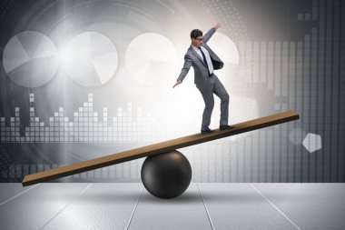 Top ve tahterevalli üzerinde denge kurmaya çalışan bir işadamı