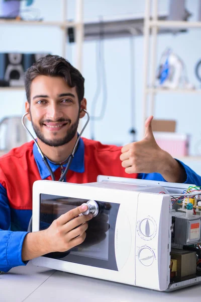 Young repairman fixing and repairing microwave oven — Stock Photo, Image