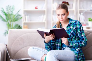 Kız öğrenci kanepede oturan kitap okuma