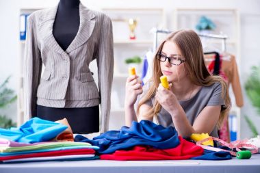 Atölyede çalışan genç bayan terzi yeni elbise üzerinde çalışıyor.