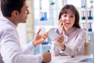 Estetik cerrah kadın yüzü ameliyatına hazırlanıyor