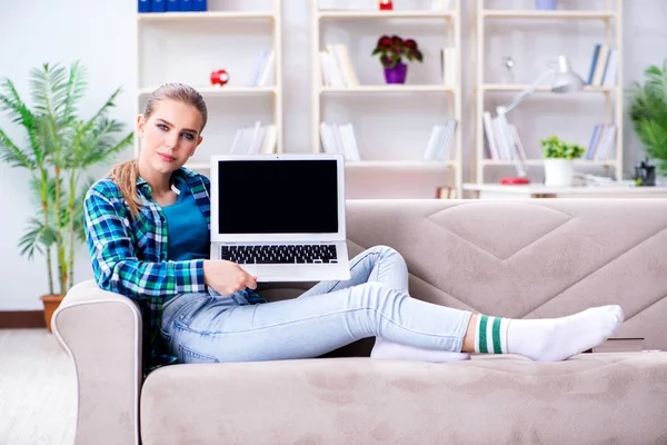 Vrouwelijke student zittend op de bank met laptop — Stockfoto