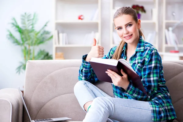 Studentka čtení knihy sedí na pohovce — Stock fotografie