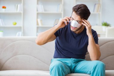 Genç adam estetik cerrahi burnundan sonra evde iyileşiyor.