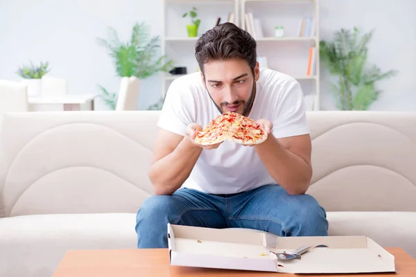 Мужчина ест пиццу, наслаждаясь домашним отдыхом — стоковое фото