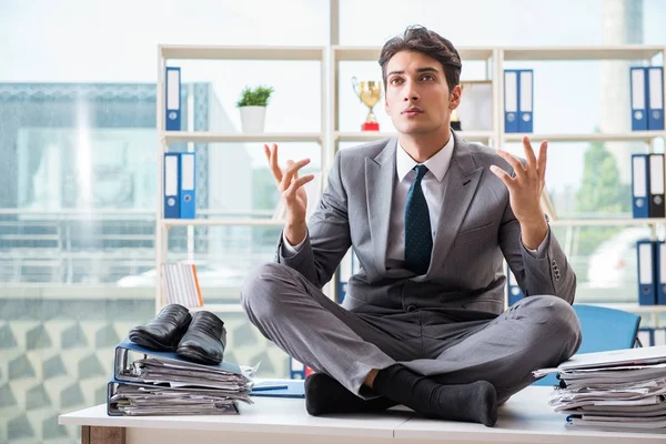 Businessman sitting on top of desk in office — Stock Photo, Image