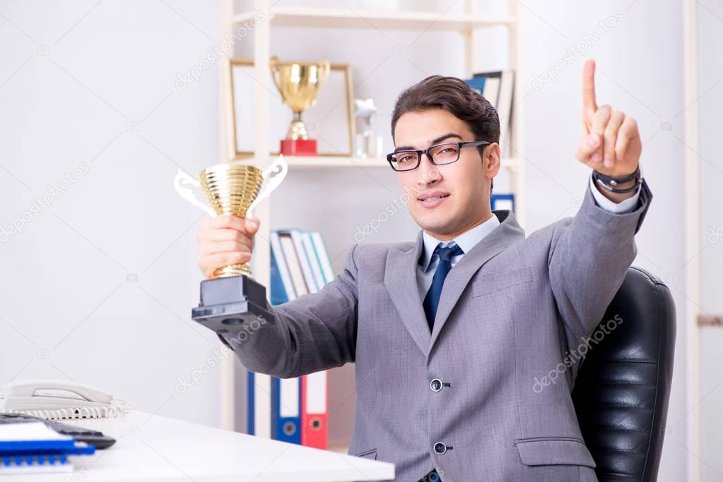 Businessman with prize cup for achievements in office