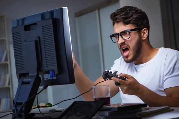 Jovem jogando jogos longas horas atrasado no escritório — Fotografia de Stock