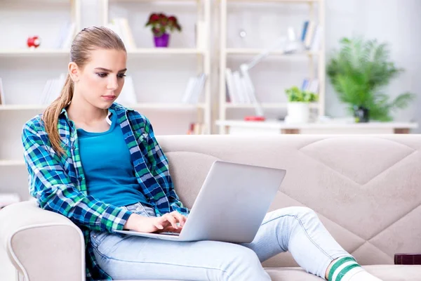 Kanepede dizüstü bilgisayarla oturan bir kız öğrenci. — Stok fotoğraf