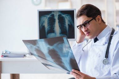 Doktor radyoloji uzmanı röntgen görüntülerine bakıyor.