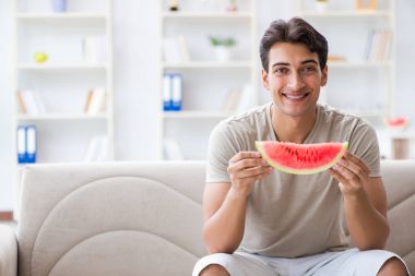 Evde karpuz yiyen bir adam.