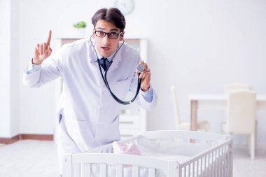 Erkek çocuk doktoru bebek yatağının yanında muayene etmeye hazırlanıyor.
