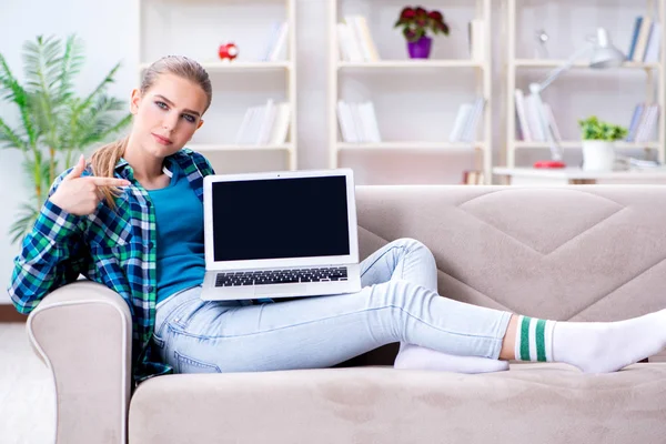 Kvinnlig student sitter i soffan med laptop — Stockfoto