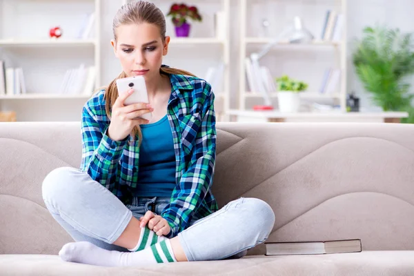 Female student sitting on the sofa with mobile — Stock Photo, Image