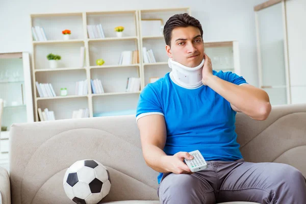목에 부상을 입은 남자가 집에서 축구를 보고 있는 모습 — 스톡 사진