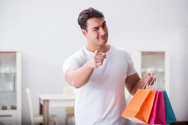 Joven con bolsa de regalo en casa preparando sorpresa para la esposa —  Fotos de Stock