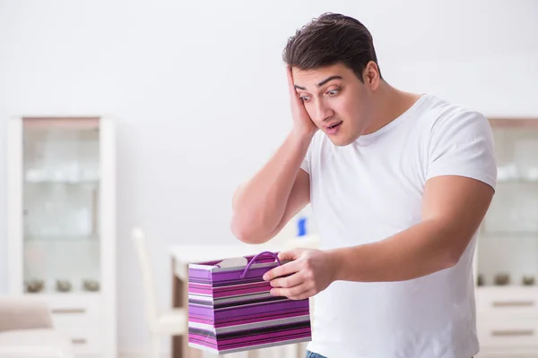 Young man with gift bag at home preparing suprise for wife — Stock Photo, Image