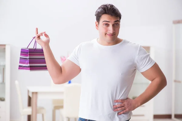 Joven con bolsa de regalo en casa preparando sorpresa para la esposa —  Fotos de Stock