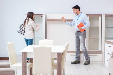 Satıcı mobilya dükkanındaki kadın müşteriye açıklama yapıyor.